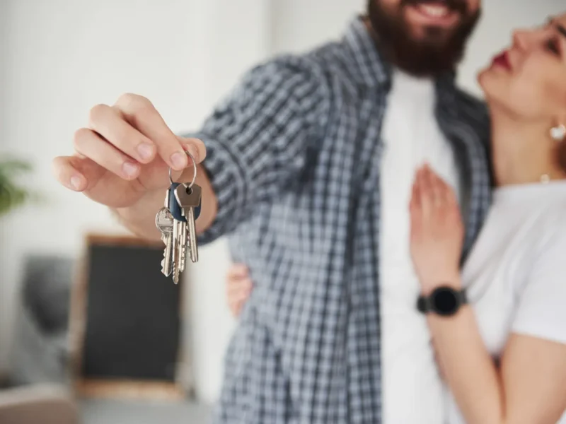 Pareja feliz mostrando llaves de su nuevo hogar, simbolizando la compra de una casa y el inicio de una nueva vida juntos.
